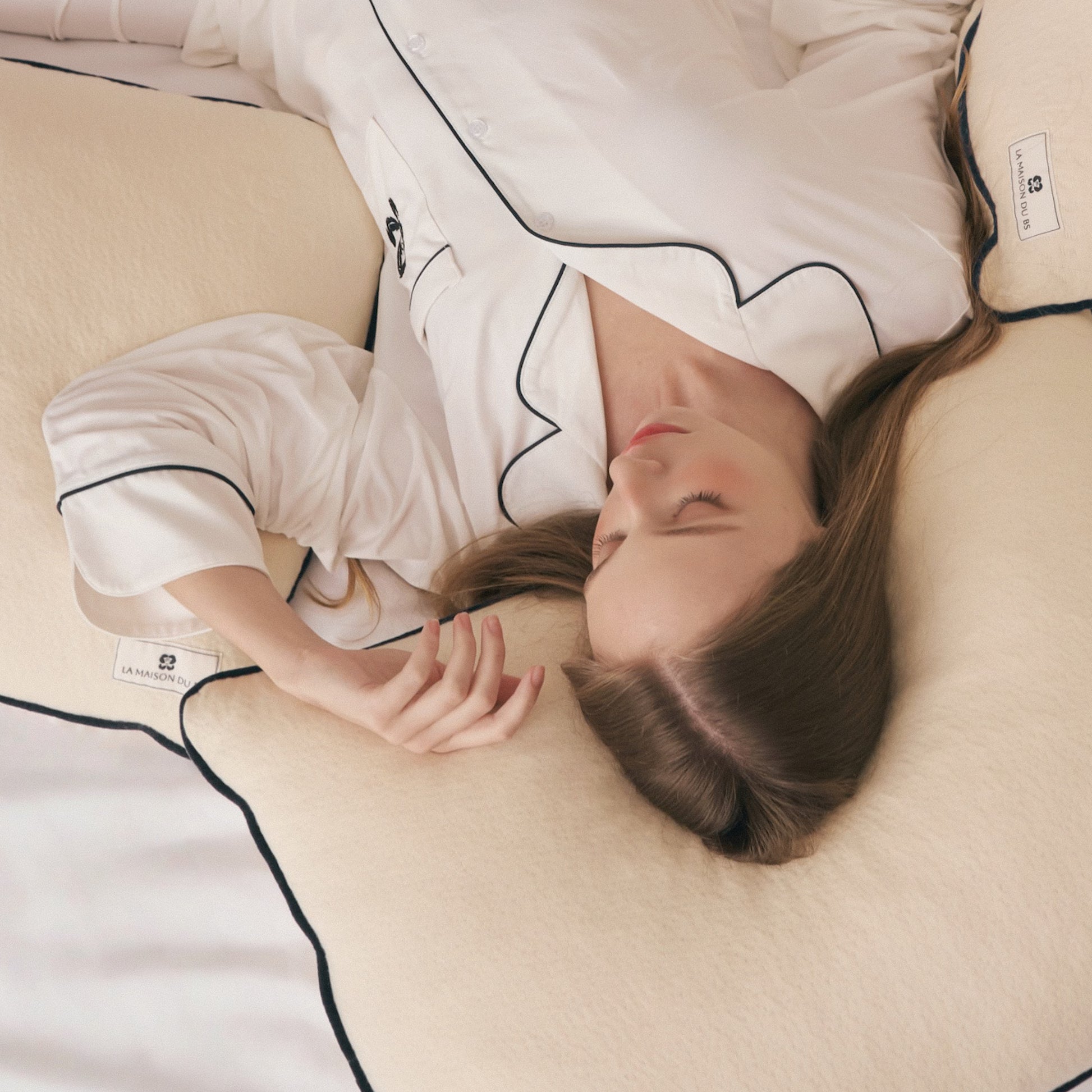 ผู้หญิงหลับอย่างผ่อนคลายบนหมอนลาเท็กซ์ออร์แกนิกจาก La Maison du BS ที่หุ้มด้วยปลอกผ้าฝ้ายออร์แกนิก โอบรับศีรษะและต้นคอ เหมาะสำหรับผู้ที่มองหาหมอนเพื่อสุขภาพและหมอน vegan-friendly ที่ผลิตจากวัสดุธรรมชาติ