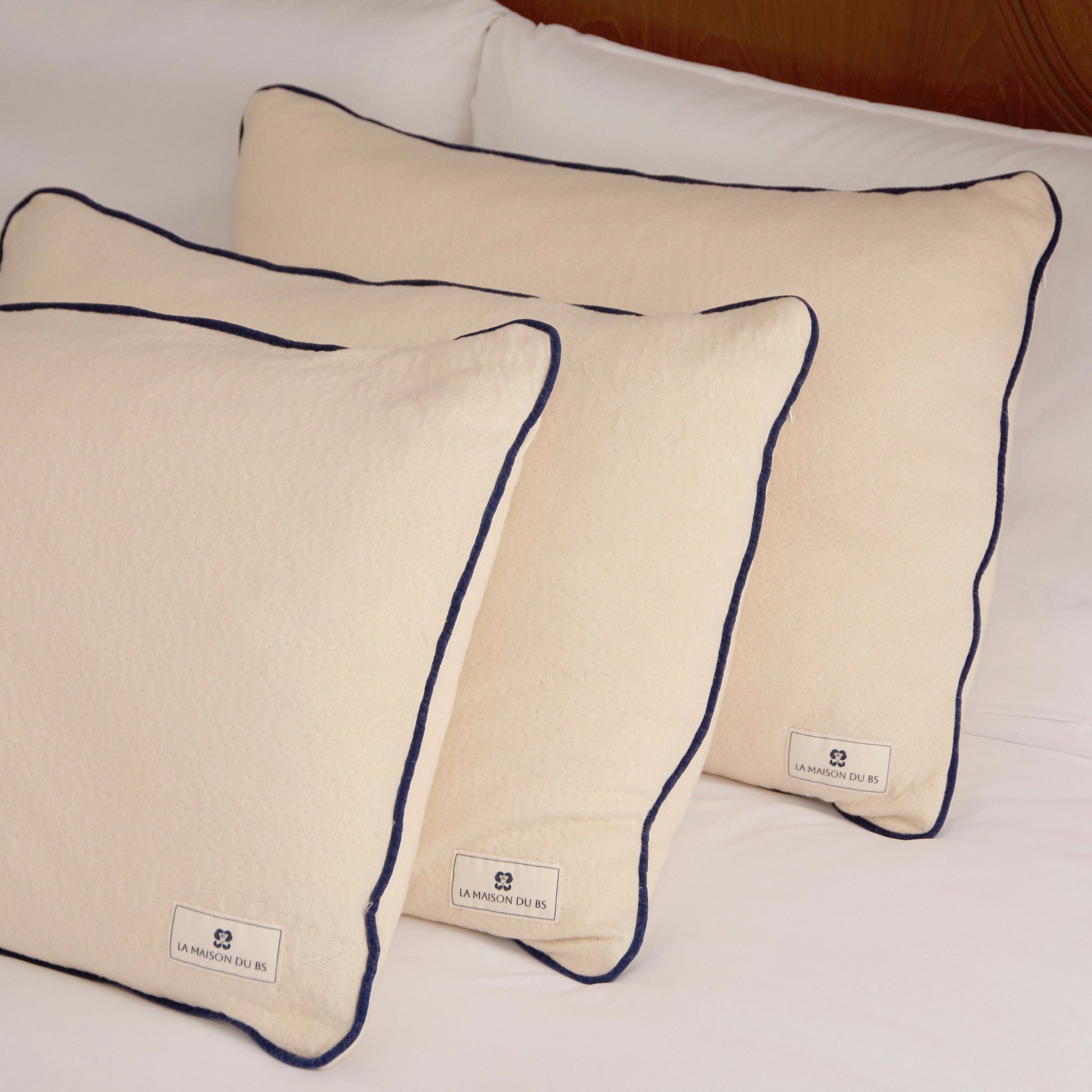 หมอนลาเท็กซ์ออร์แกนิกจาก La Maison du BS วางเรียงบนเตียง พร้อมปลอกผ้าฝ้ายออร์แกนิกแต่งขอบสีน้ำเงิน ใช้วัสดุธรรมชาติ ปราศจากสารสังเคราะห์ เหมาะสำหรับผู้ใช้ที่มองหาหมอนที่เป็น vegan-friendly และช่วยเรื่องการนอนหลับที่ดี