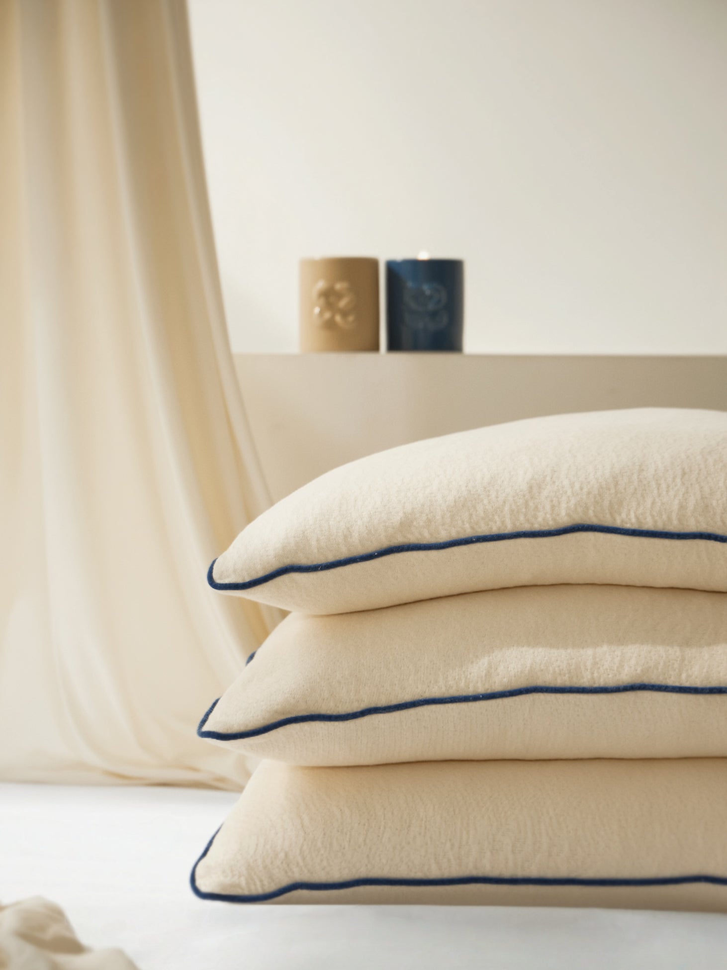 หมอนลาเท็กซ์ออร์แกนิกจาก La Maison du BS วางซ้อนกันสามใบ พร้อมเทียน natural wax essential oil candleในบรรยากาศอบอุ่น สะท้อนความสบายแบบธรรมชาติ เหมาะสำหรับผู้ที่มองหาหมอนเพื่อสุขภาพ ปลอดสารเคมี และ vegan-friendly